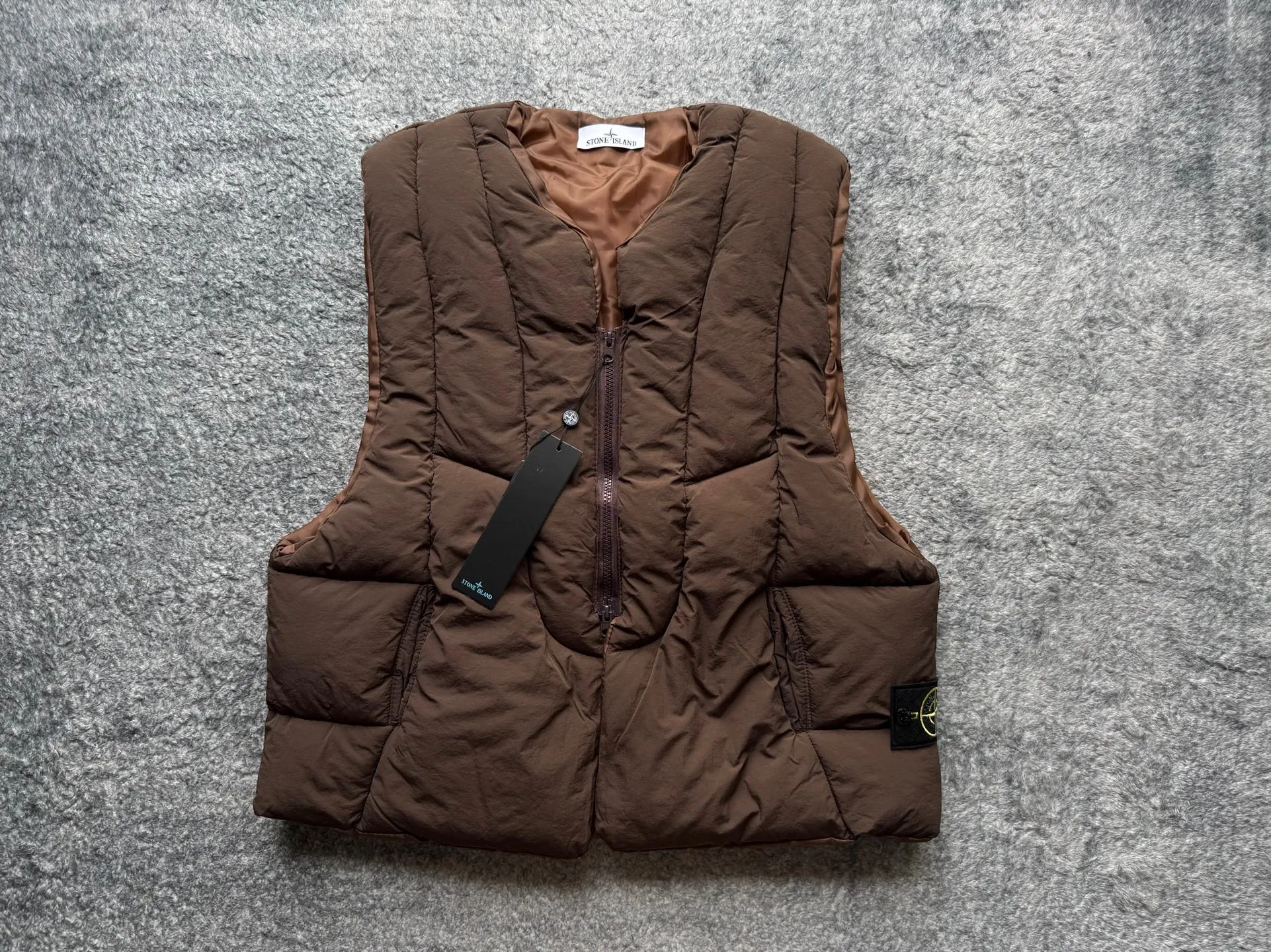 P280 Stone Island 25Fw Stone Island Linear Split Silhouette Cotton-Filled Deconstructed Waistcoat Jacket Stone Island's 2025 Grand Offering The outer layer is made of high-quality wrinkled nylon fabric, and the inner layer is filled with high-comfort and warm velvet cotton. The filling amount is very sufficient and the overall clothing is very full. The upper body silhouette and warmth are well guaranteed. The front and rear split line design is simple without losing details. The double zipper puller zipper increases practicality. The short design is very suitable for trendy matching in all seasons. It is very effective whether it is paired with a sweatshirt or a jacket. The basic black and chocolate brown meet the requirements of jumping in color and being versatile. It is a powerful tool for matching lazy suits when going out on the street. The classic emblem armband of Stone Island highlights the brand tension. It is first released on the entire network. Manufactured by a large factory. Complete with three-label accessories. Same style for men and women. Color: brown/black Size: m～xl